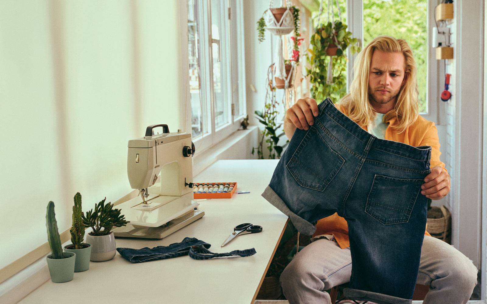 Man sitting at home trying to fix his trousers