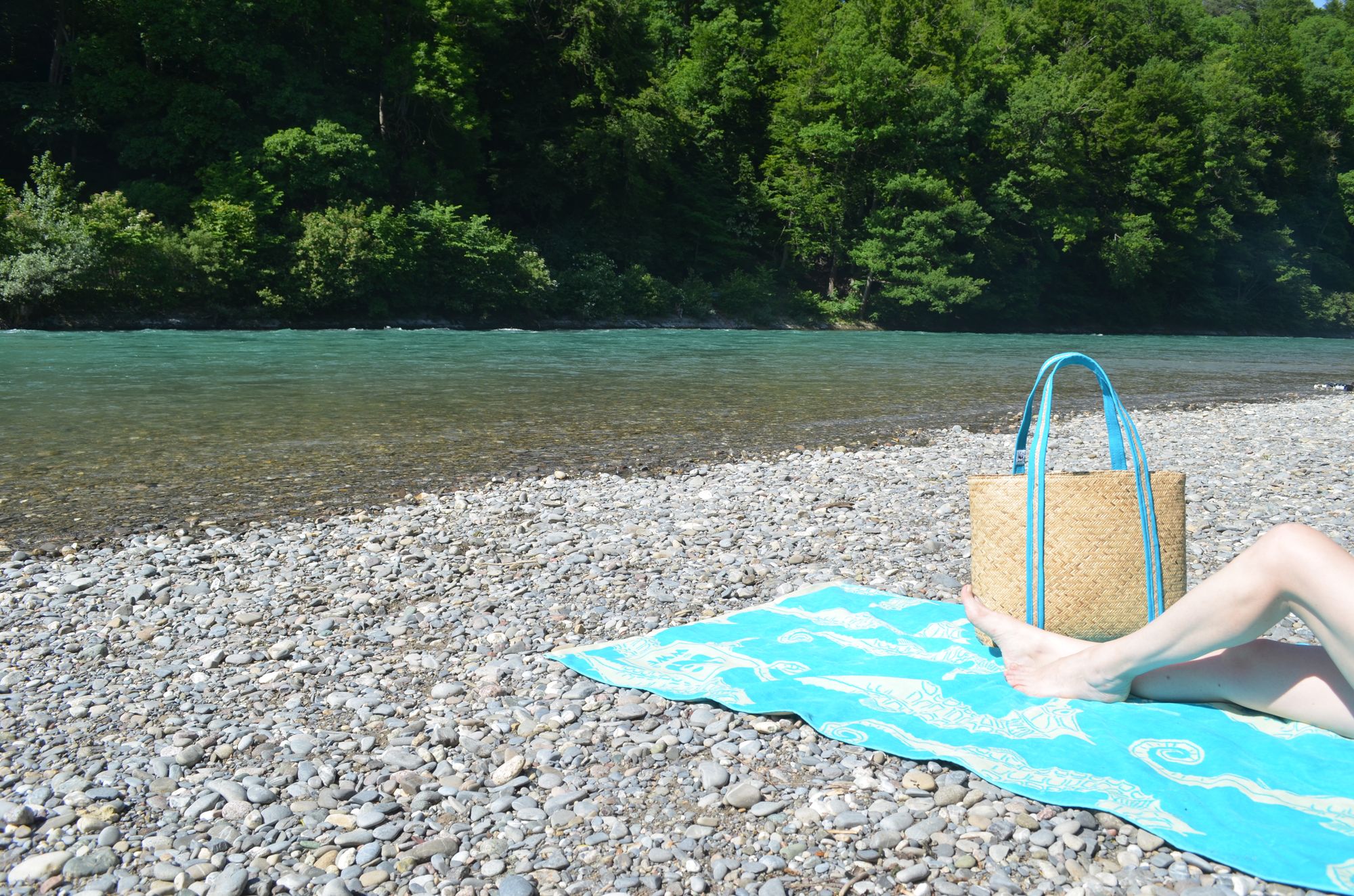 Strandtasche und Badetuch am Fluss