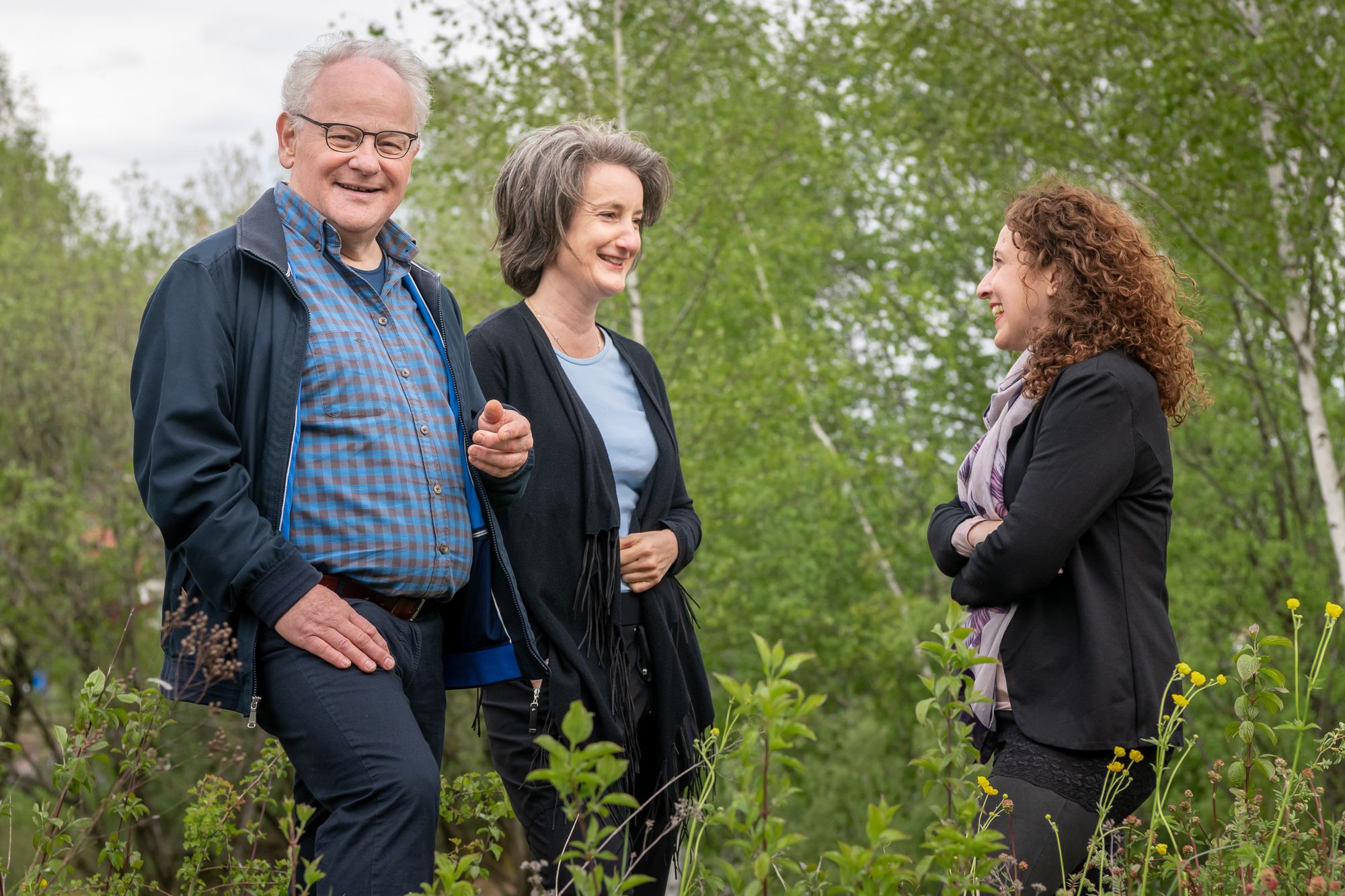 One gentleman and two ladies in nature chatting
