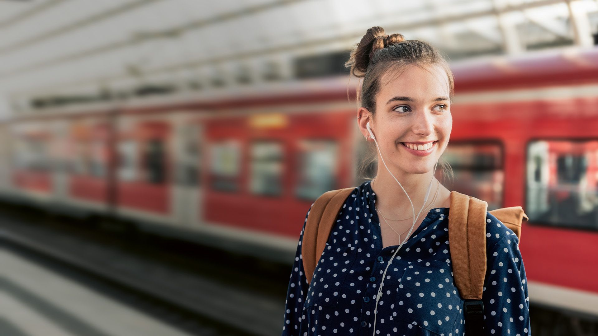 Frau steht lächelnd am Bahnhof 