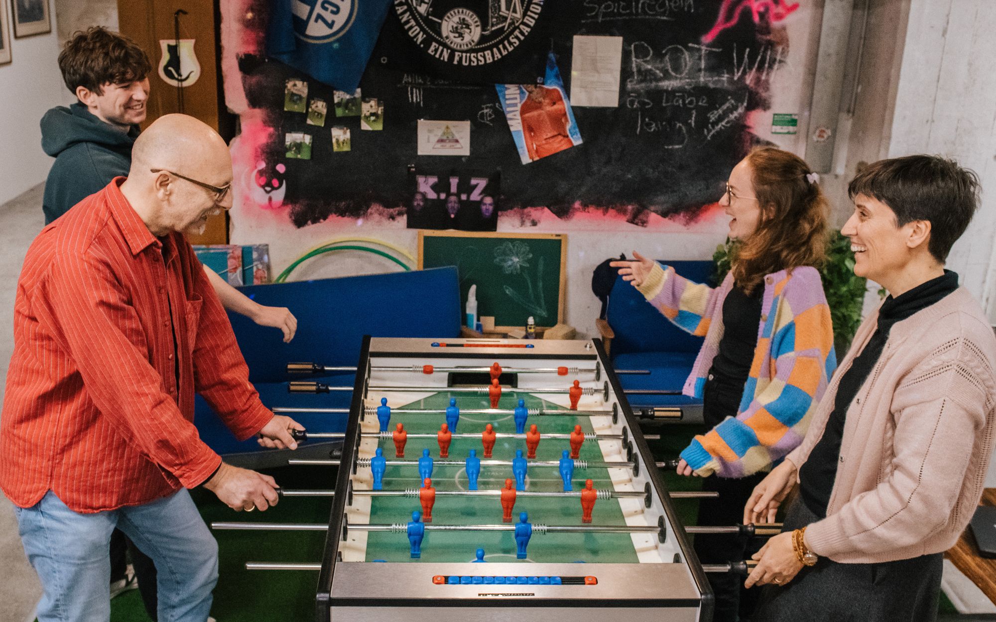 four co workers playing table football