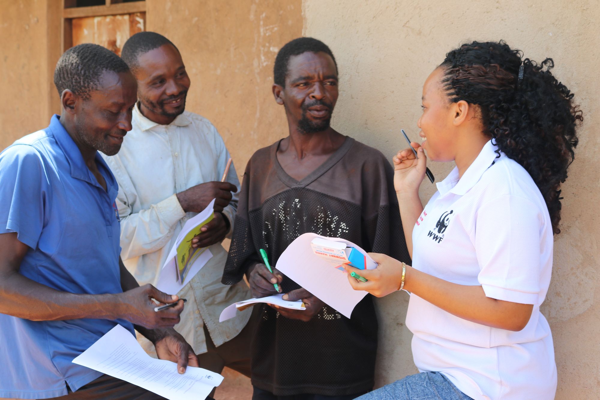 Eine Frau im WWF Tshirt spricht zu einer Gruppe Männer