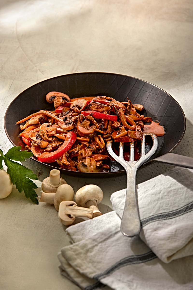 Ein Gemüse-Pilz-Stroganof auf einem schwarzen Teller