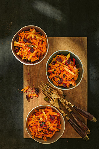 Drei Schalen mit Kürbis-Apfel Salat auf einem Holzbrett