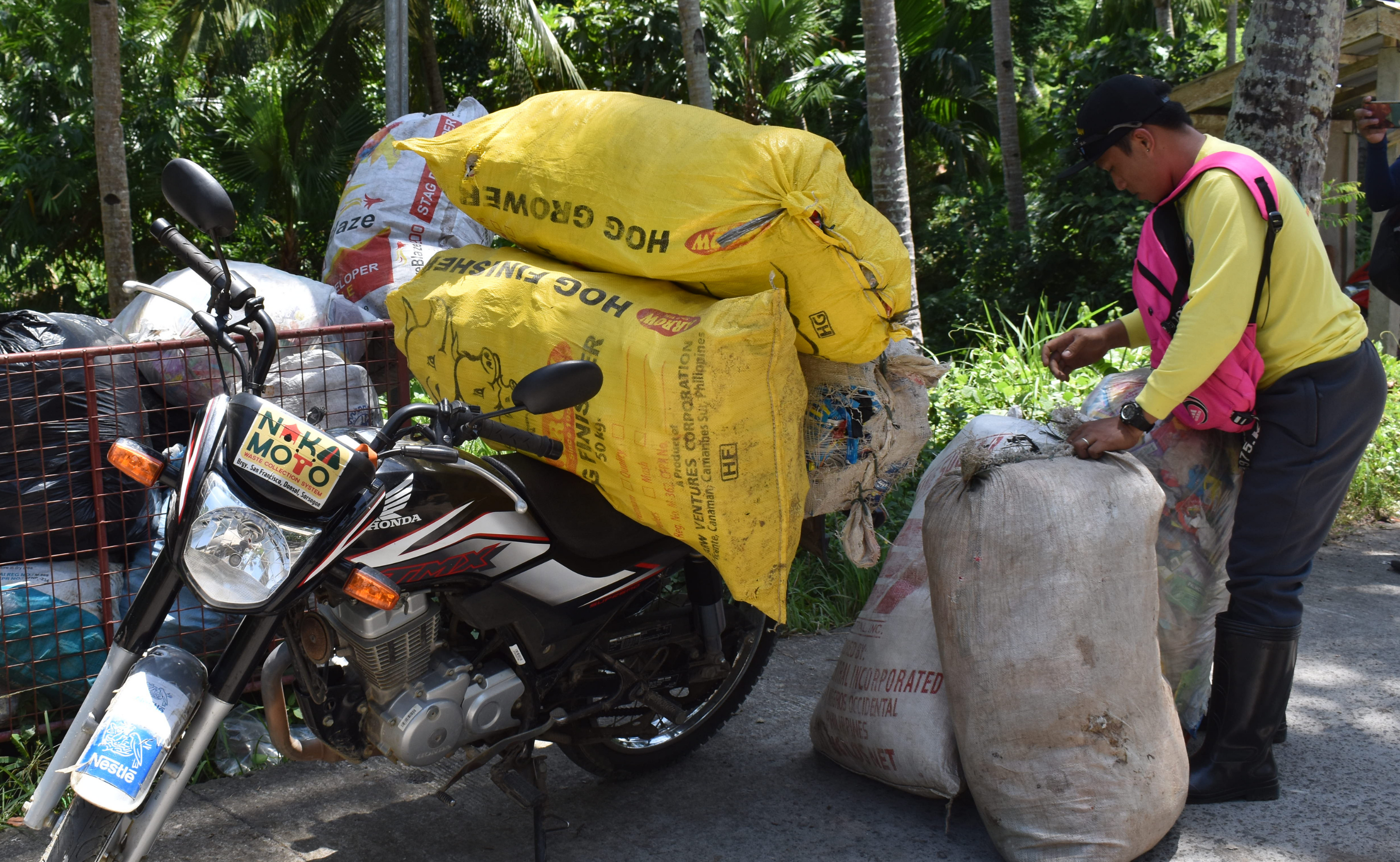 Un homme ramasse des déchets plastiques dans de grands sacs, Donsol, Philippines