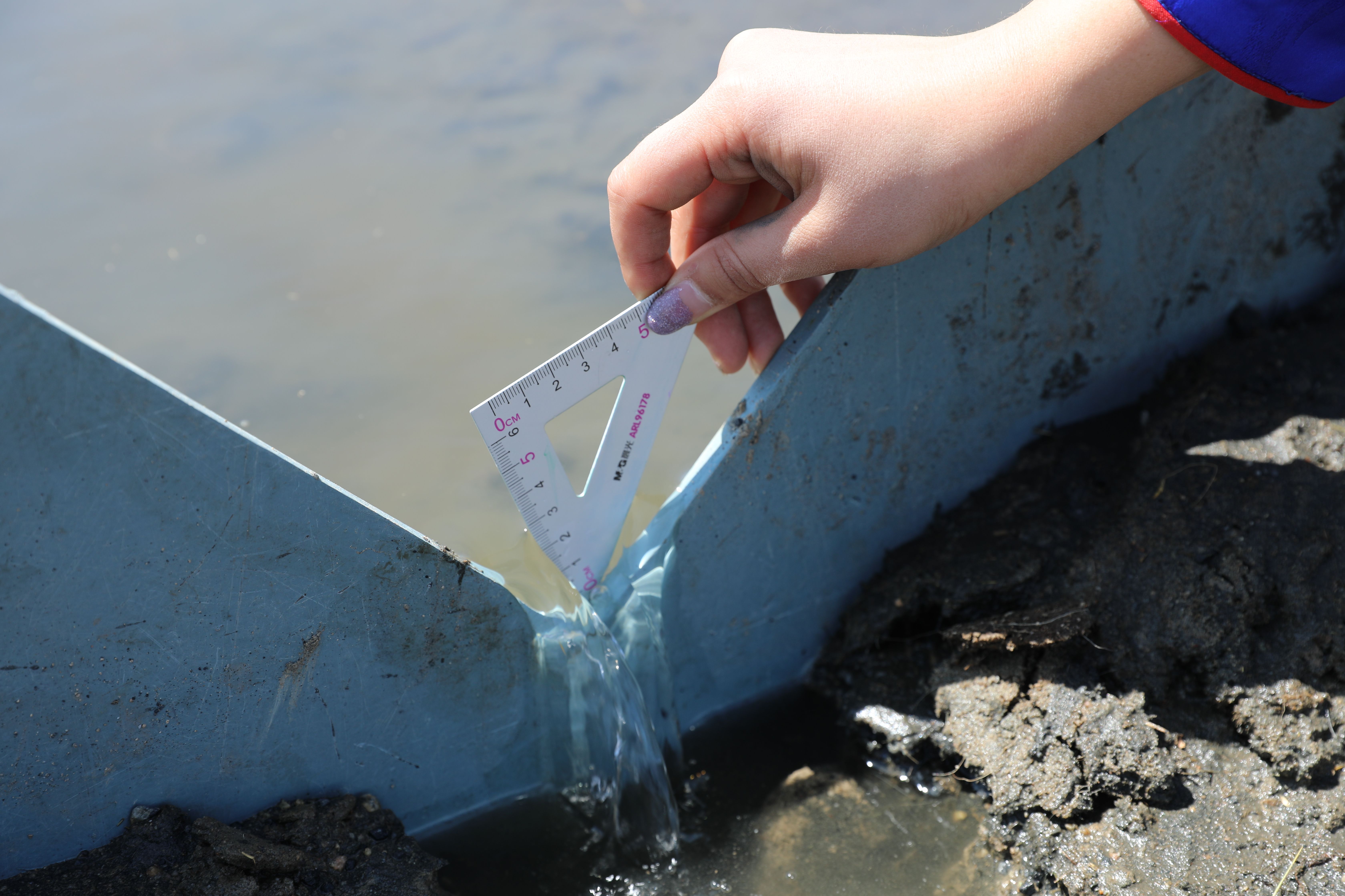Eine Person beim Messen des Abflusses an einer Quelle, Mongolei