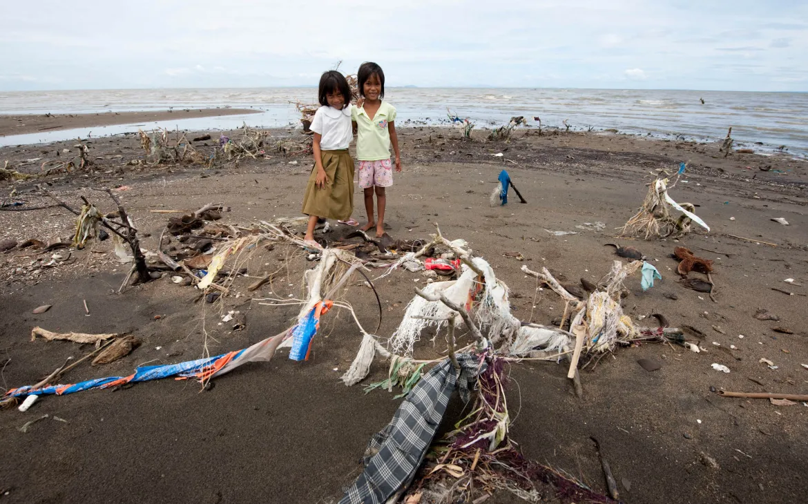 Zwei Mädchen posieren vor Plastikmüll auf den Phlilippinen
