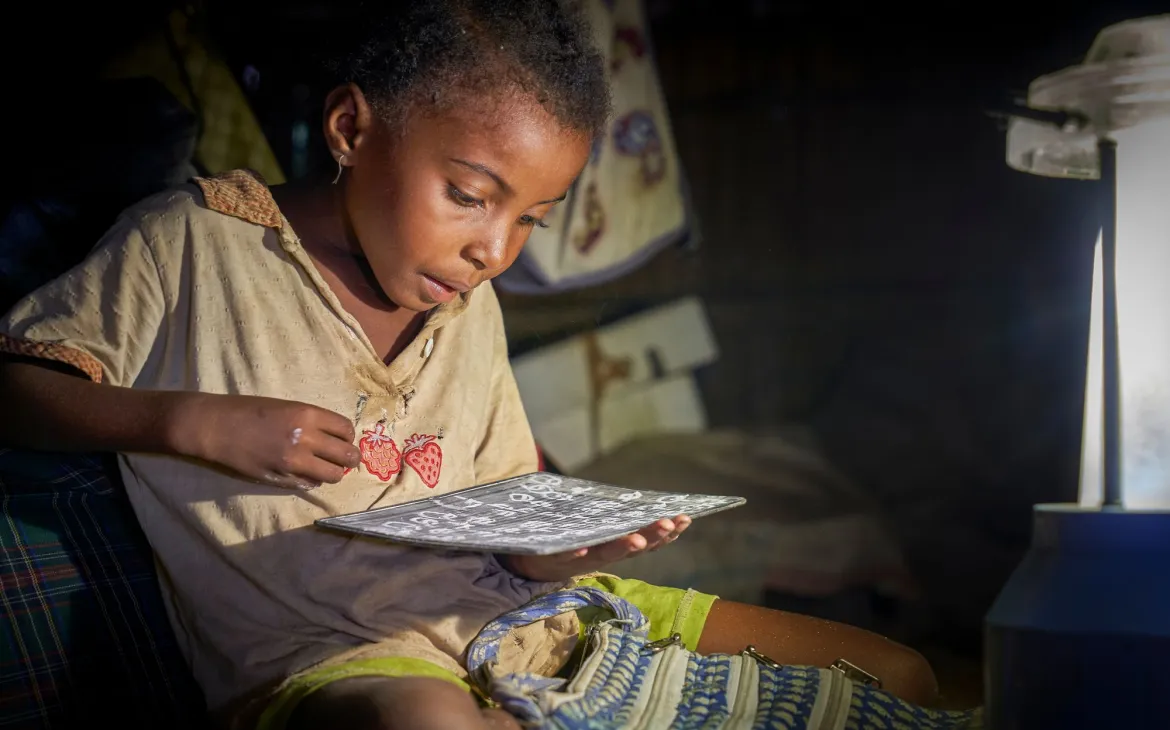 Schulkind in Madagaskar macht im Licht einer Solarlampe Hausaufgaben