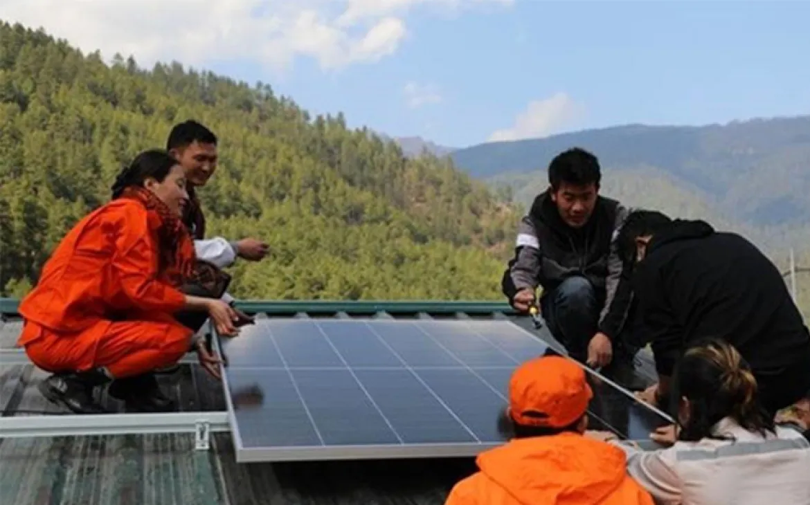 Ein Solarpanel wird von mehreren Menschen auf einem Wellblechdach installiert