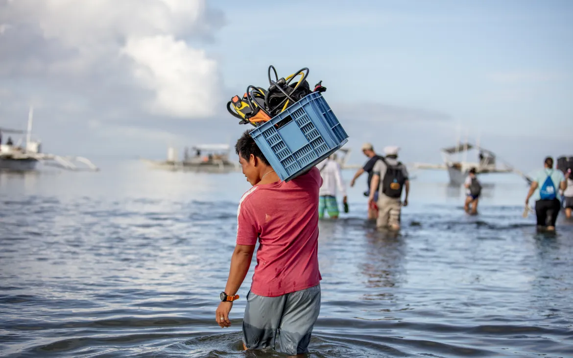 A dive guide carries equipment to his boat in Donsol, Philippines.