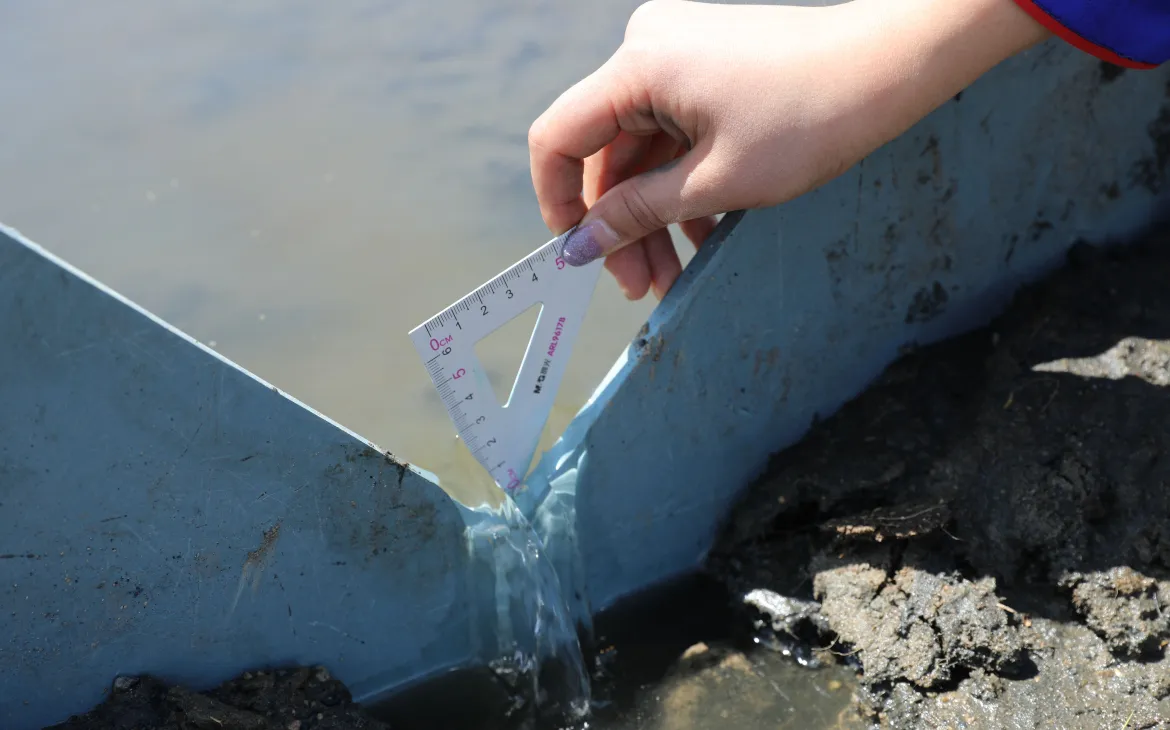 Eine Person beim Messen des Abflusses an einer Quelle, Mongolei