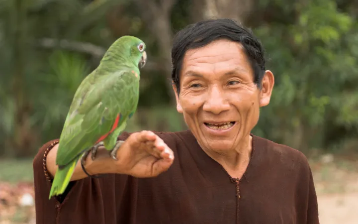 Jorge vom Ashaninka Volk in Peru mit einem grünen Papageien (Amazona amazonica)