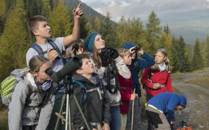 Kinder im Nationalparklager des WWF beobachten durch Fernrohre die Natur.