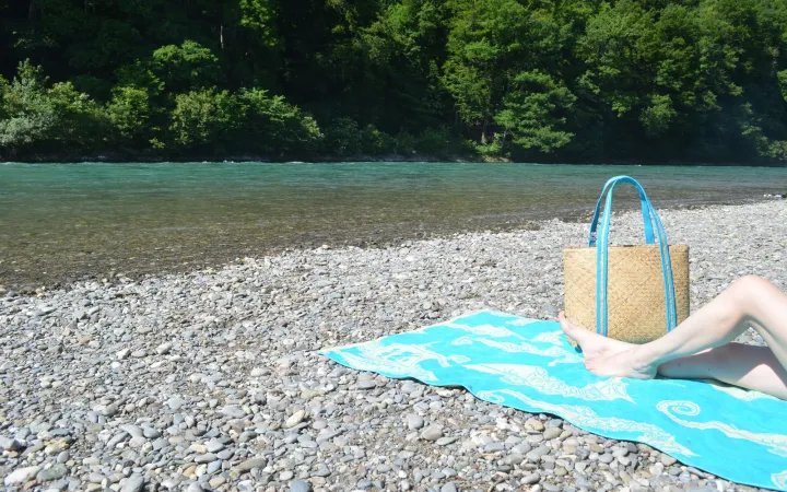Strandtasche und Badetuch am Fluss