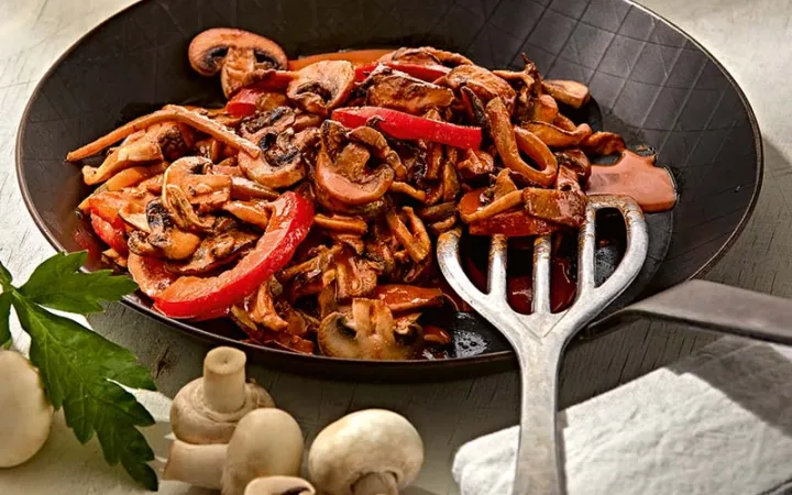 Ein Gemüse-Pilz-Stroganof auf einem schwarzen Teller