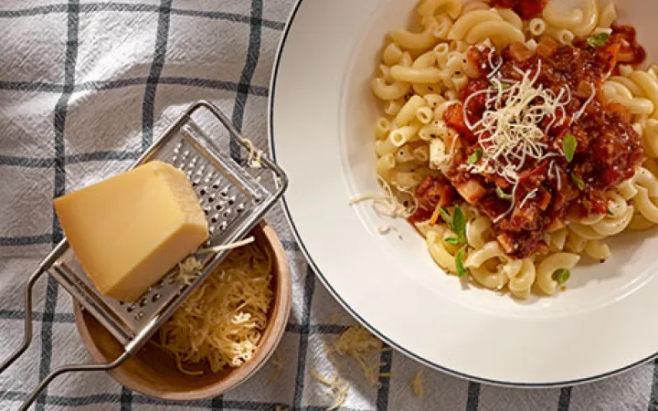 Ein Teller mit Teigwaren und daneben ein Stückkäse auf einer Raffel