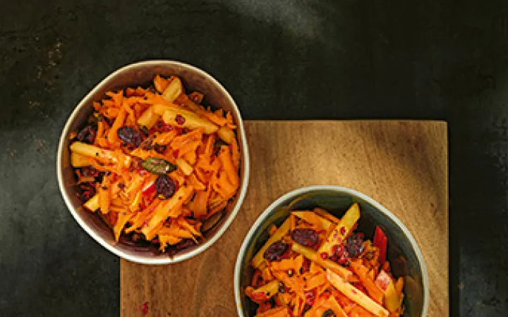 Drei Schalen mit Kürbis-Apfel Salat auf einem Holzbrett