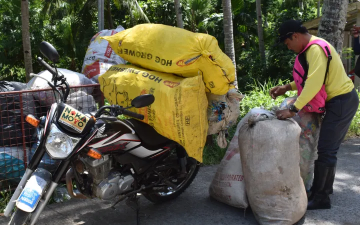 Un homme ramasse des déchets plastiques dans de grands sacs, Donsol, Philippines
