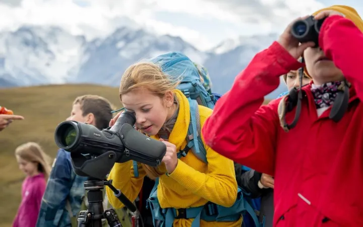 Kinder in den Bergen schauen durch Ferngläser
