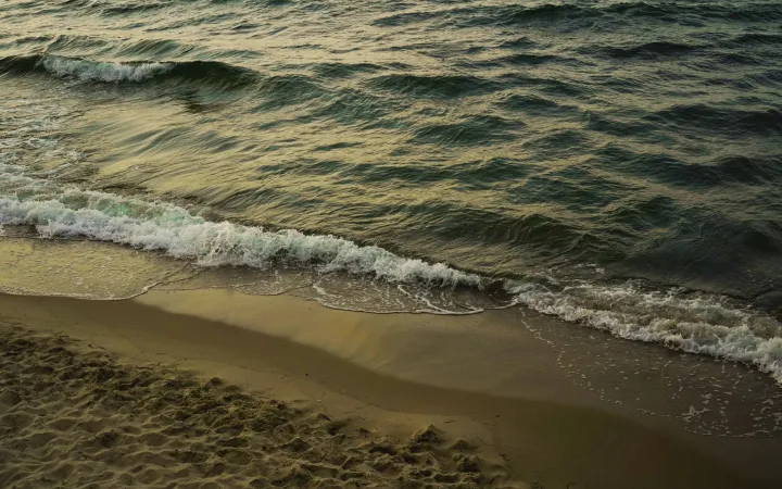 Waves braking on a sand beach, while it gets dark and the sun sets