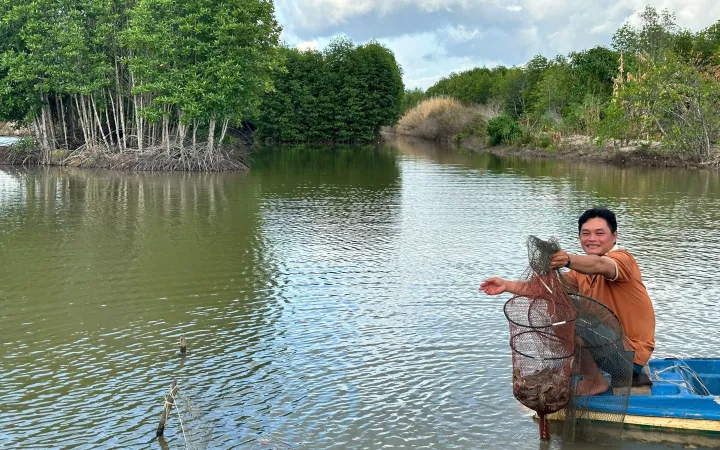 Vietnam farmer harvesting shrimp on a river