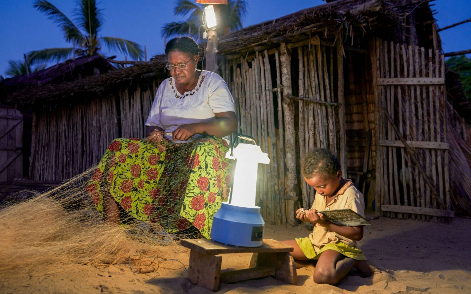 Frau flickt Fischernetz im Licht einer Solarlampe. Barefoot College Madagaskar