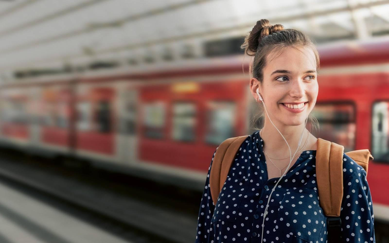 Frau steht lächelnd am Bahnhof