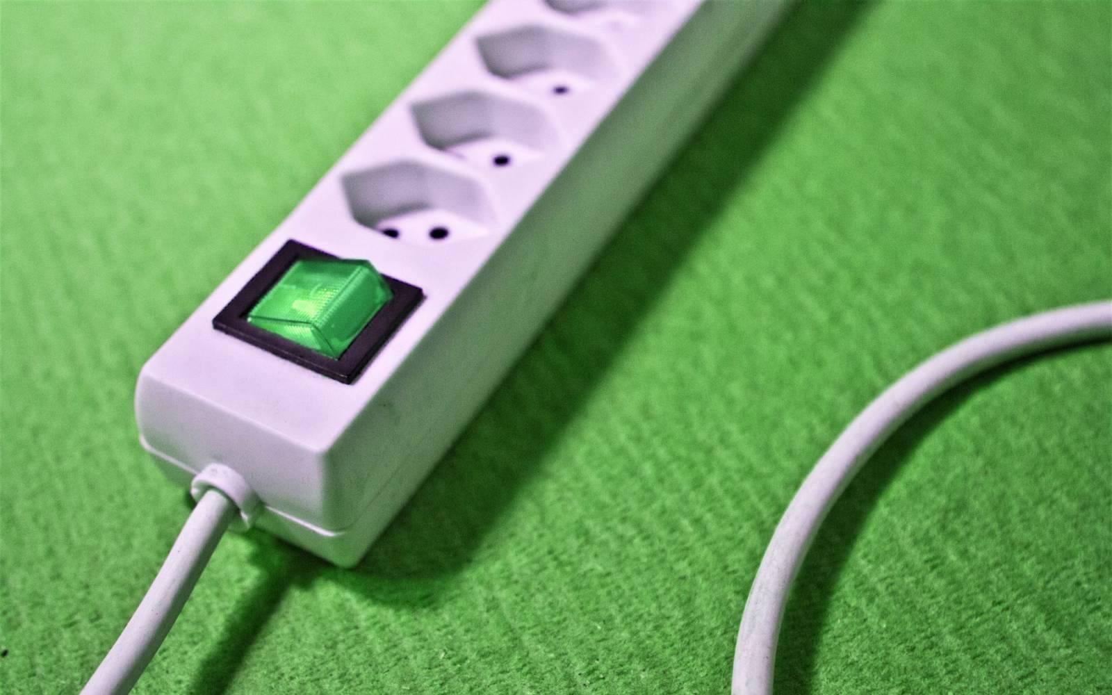 Steckleiste mit gruenem On Off-Switch auf gruenem Utnergrund
