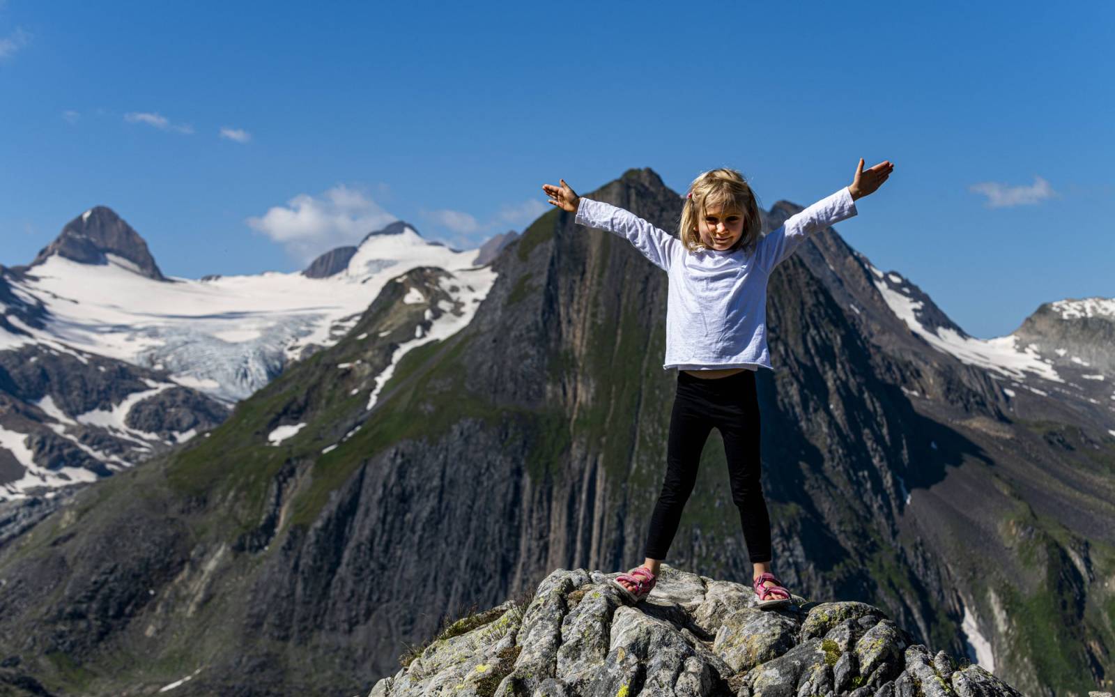 Mädchen auf einem Felsen auf dem Nufenen Pass