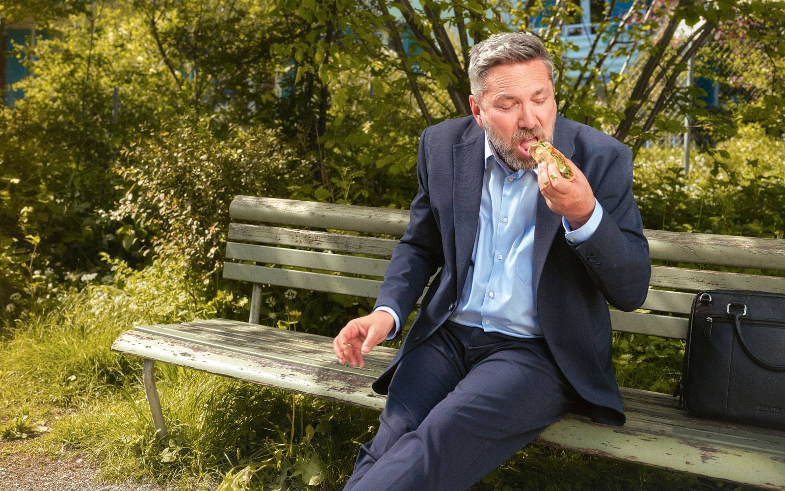 Man sitting on bench in park eating