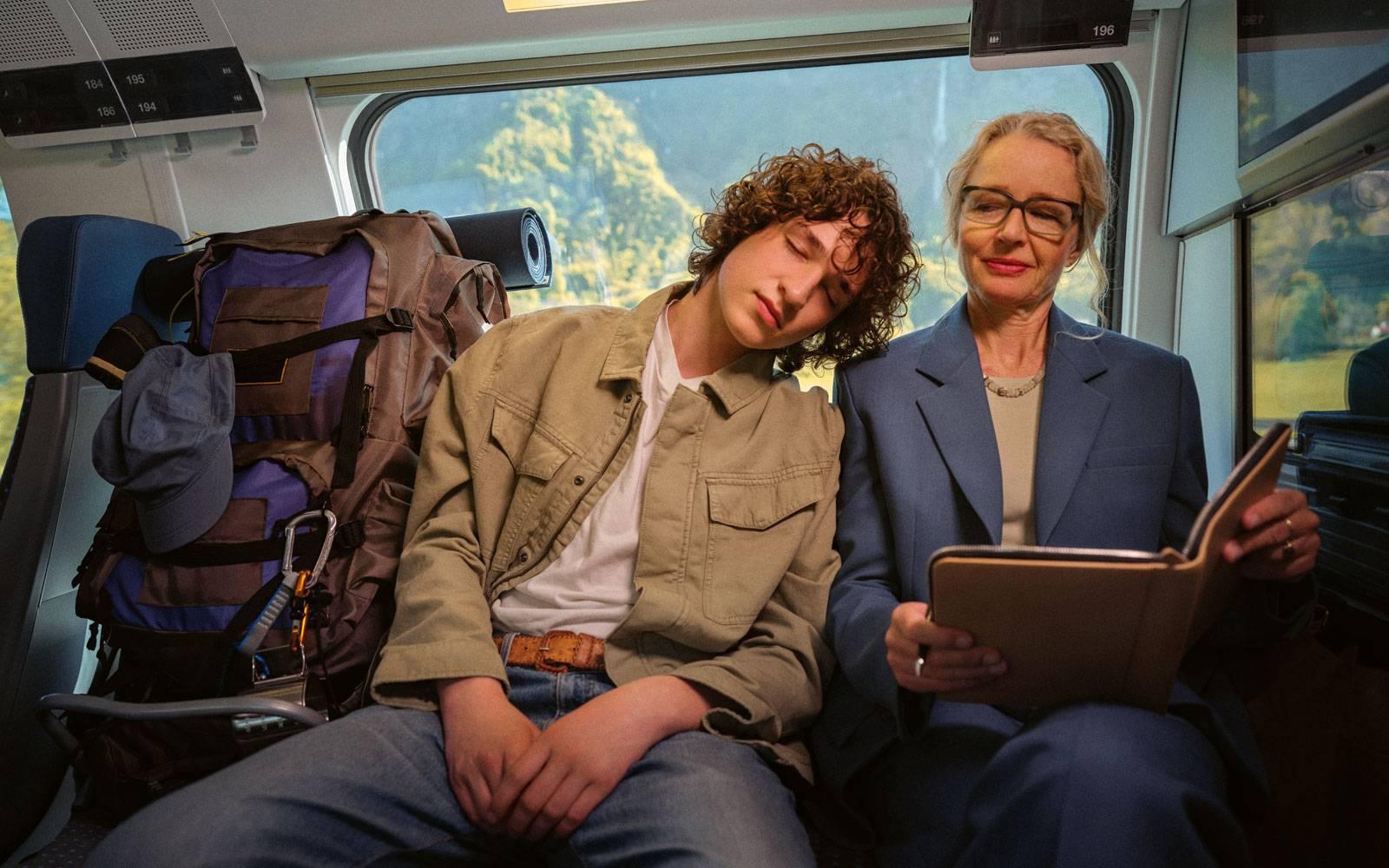 Young man falling asleep on train next to a woman
