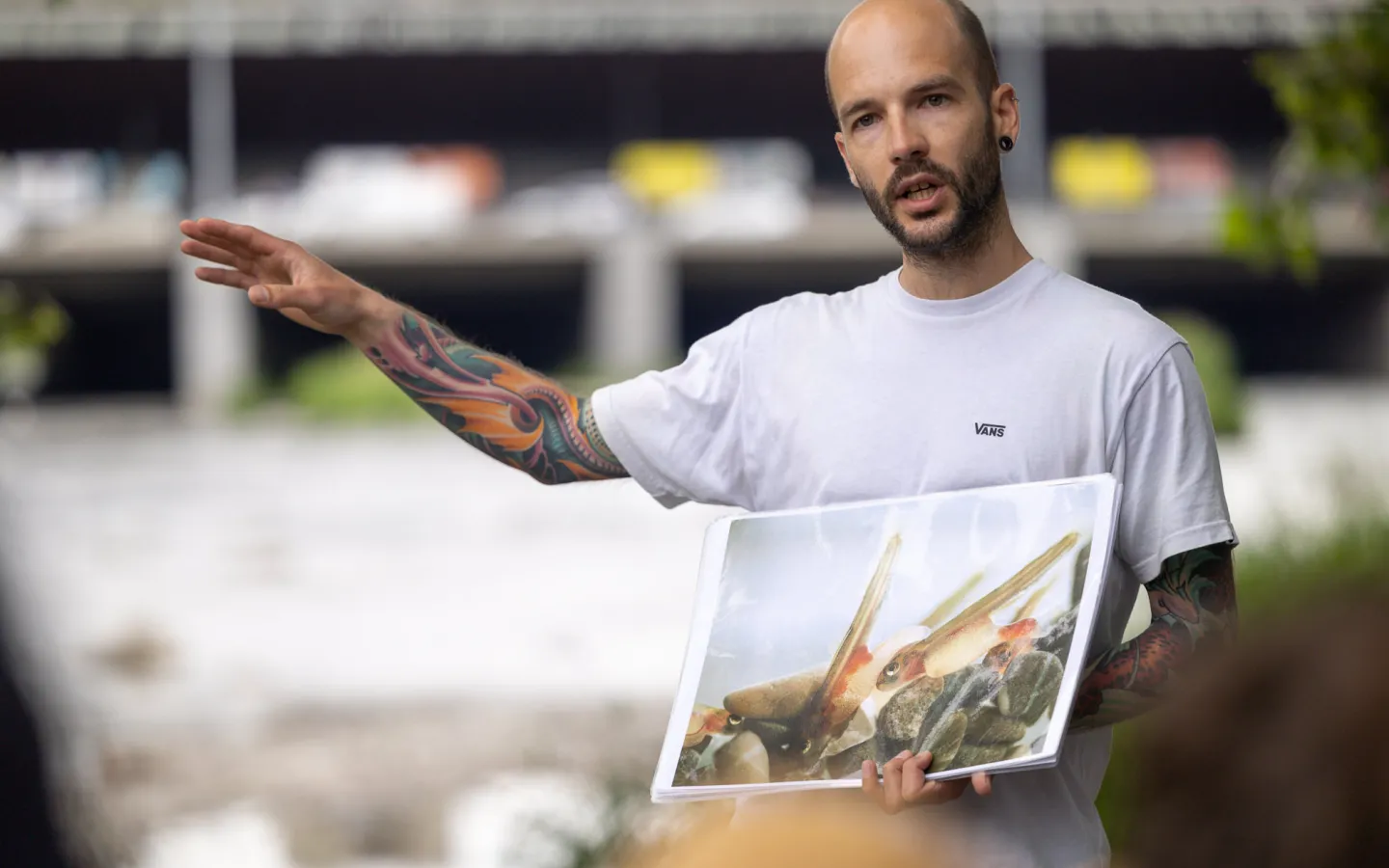 Christian Hossli in front of a river with a picture of a salmon