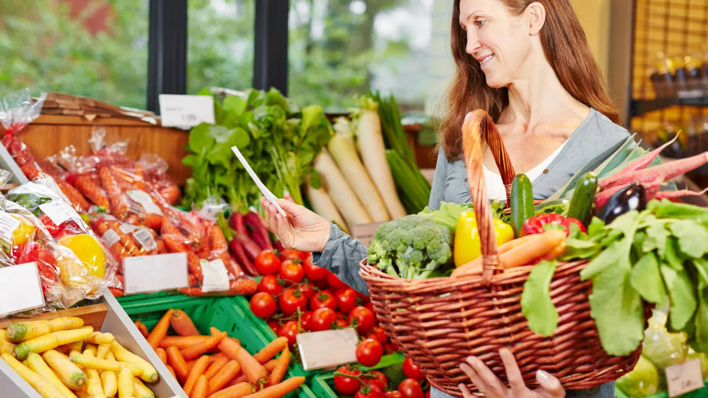Femme avec liste d'achats acheter des légumes