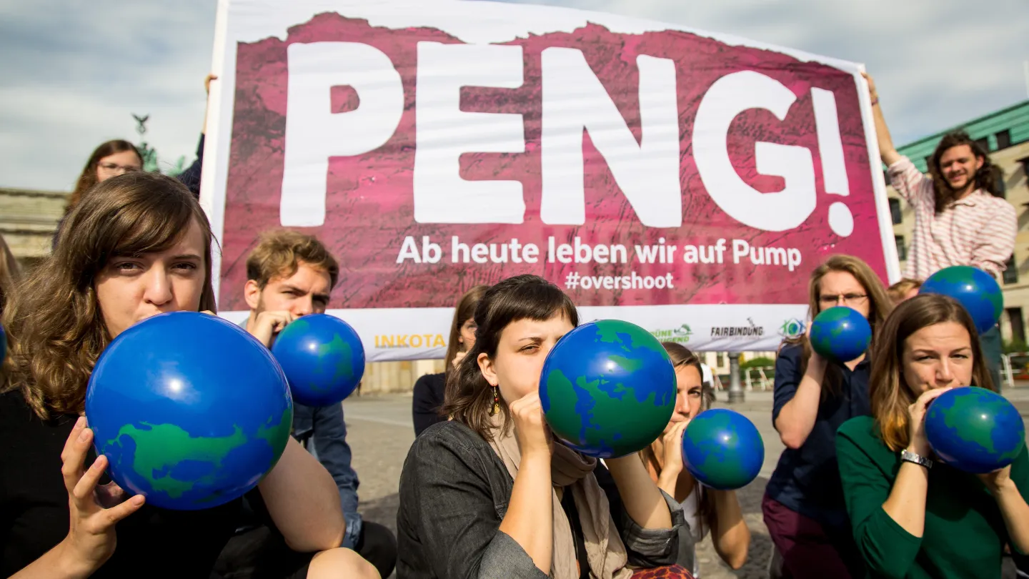 Jugendliche vor einem Plakat zum OVershoot Day