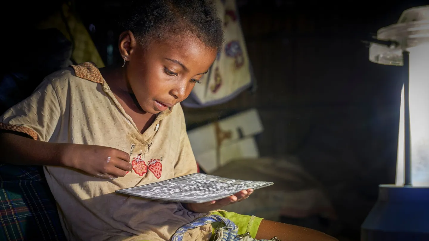 Schulkind in Madagaskar macht im Licht einer Solarlampe Hausaufgaben