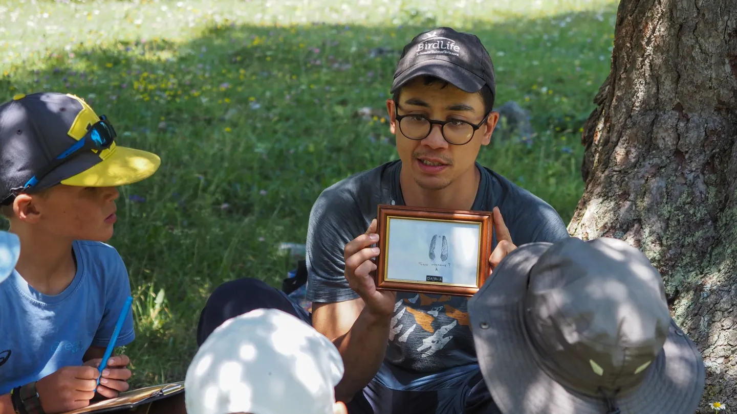 Ein Lagerleiter erklärt den Kindern Tierspuren in einem Sommerlager.